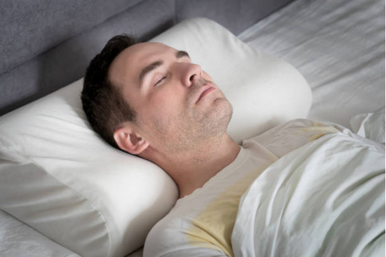 memory foam pillow contouring to cervical spine on a bed